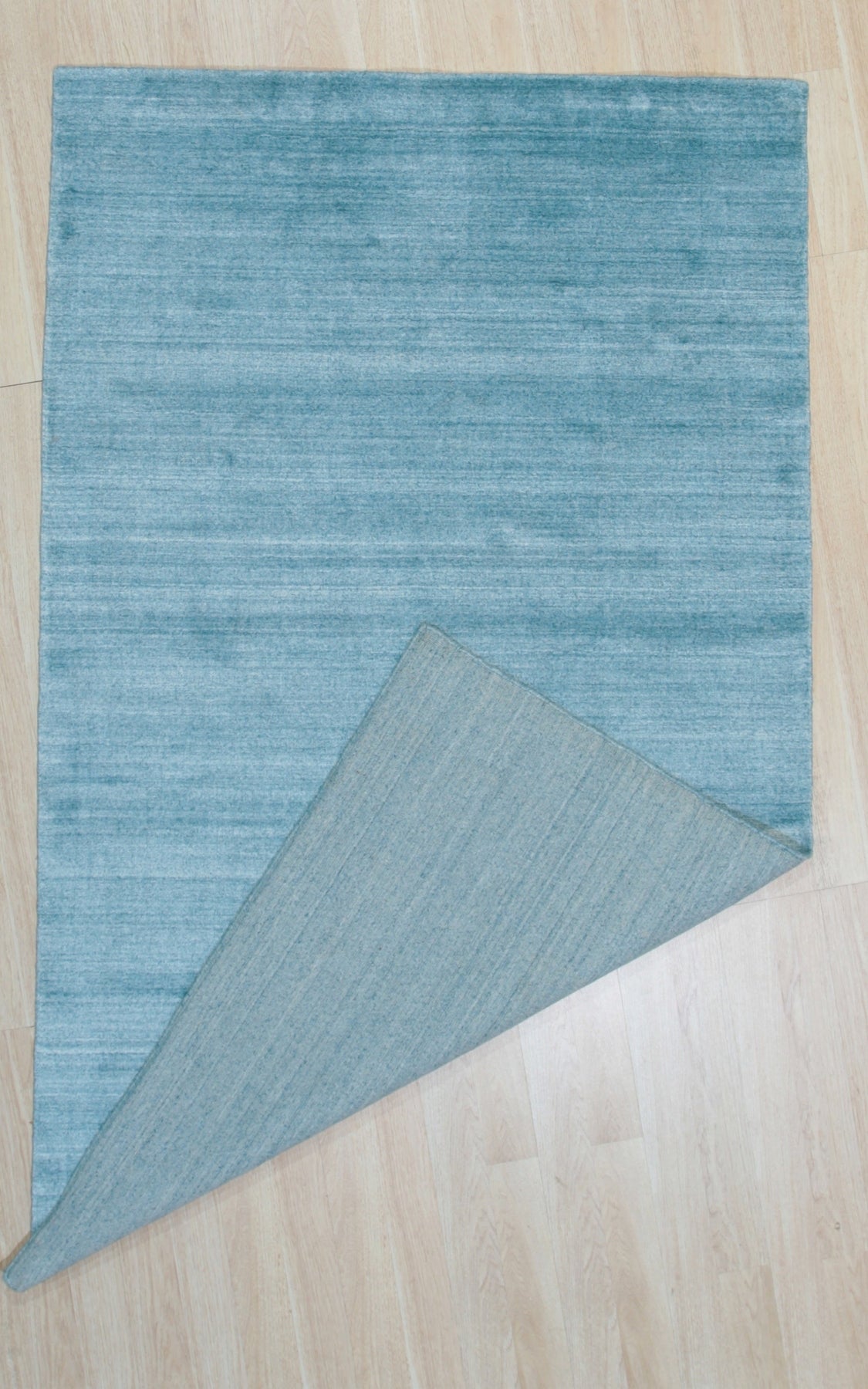 Lush Ella Blue Handmade Wool & Viscose Rug, its cool blue tones and subtle sheen creating a calming presence in a styled living space.
