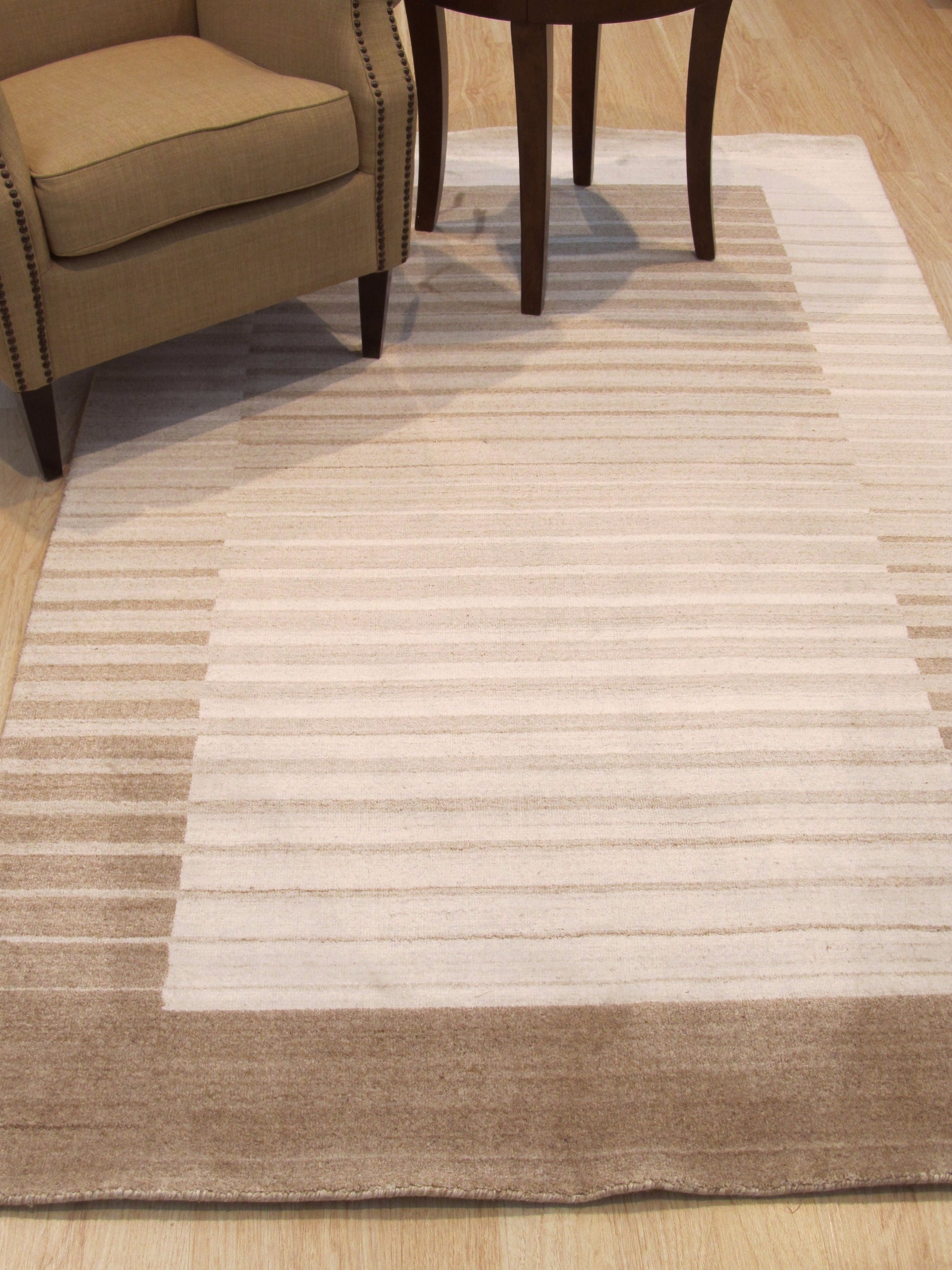 Rhea Quinn Brown Handmade Wool & Viscose Rug, blending warm browns in a subtly textured design, lies invitingly on a light hardwood floor, adding depth and organic elegance to the space.