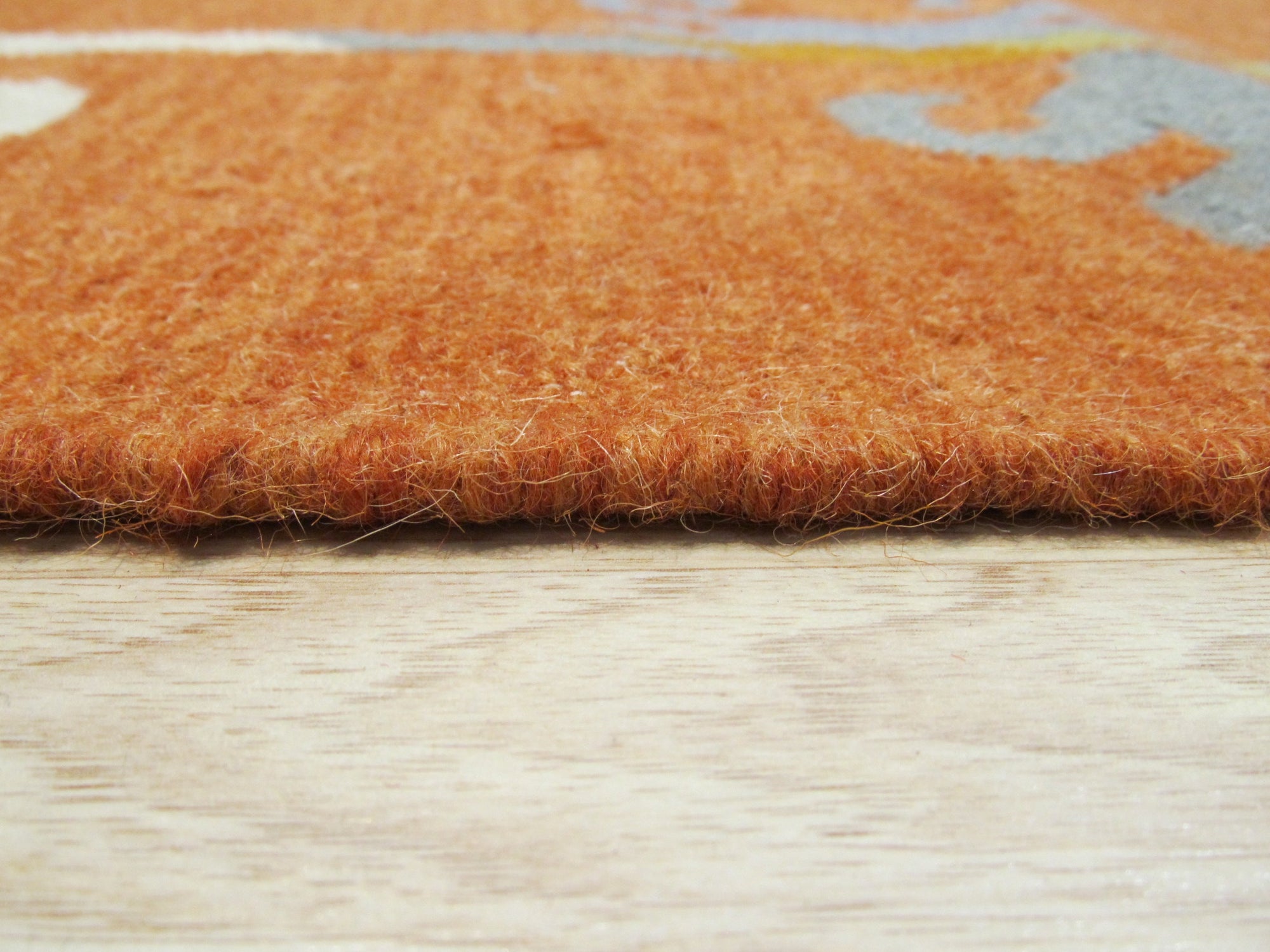 Maya Kilim Rust Flatweave Wool Rug, displaying its warm rust hues and intricate geometric patterns, seen in a brightly lit room with hardwood floors and a glimpse of modern furniture, highlighting its flatweave construction and rustic charm.