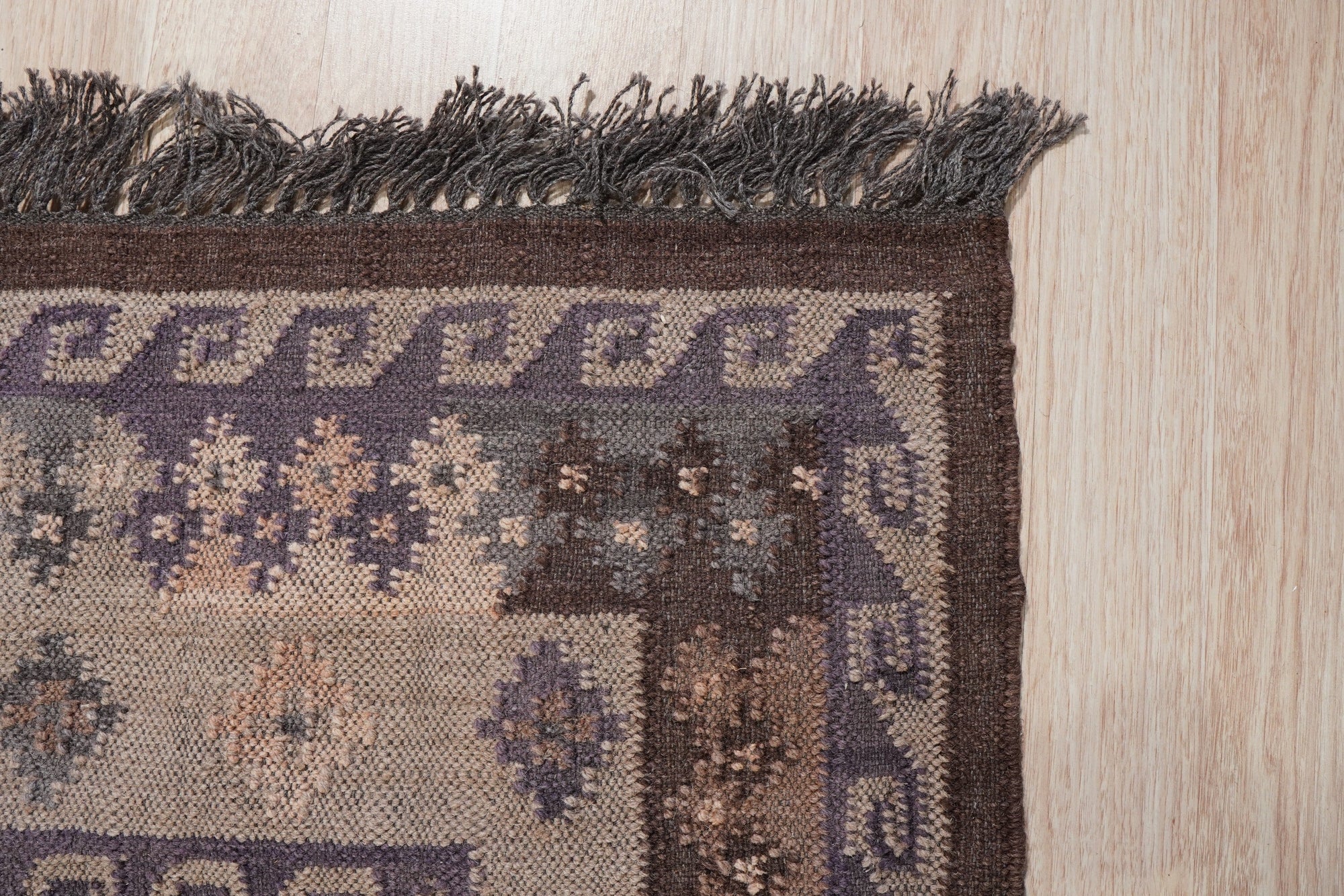 Brenda Jasmine Brown Flatweave Wool Rug, showcasing warm brown tones and a subtle geometric pattern in a well-lit living room setting, adding texture and warmth to the space.