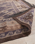 Brenda Jasmine Brown Flatweave Wool Rug, woven from wool with a flatweave construction, features brown tones and intricate patterns, complementing a naturally lit room with neutral furniture.