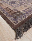 Brenda Jasmine Brown Flatweave Wool Rug, displaying its intricate geometric pattern in warm browns and creams, lies flat on a light wood floor, showcasing its soft, textured wool construction.