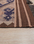 Penelope Jade Brown Flatweave Wool Rug, blending earthy browns and subtle jade tones, lies beneath a modern living space. The flatweave wool construction adds texture and warmth to the light wood flooring, creating a cozy and inviting atmosphere.