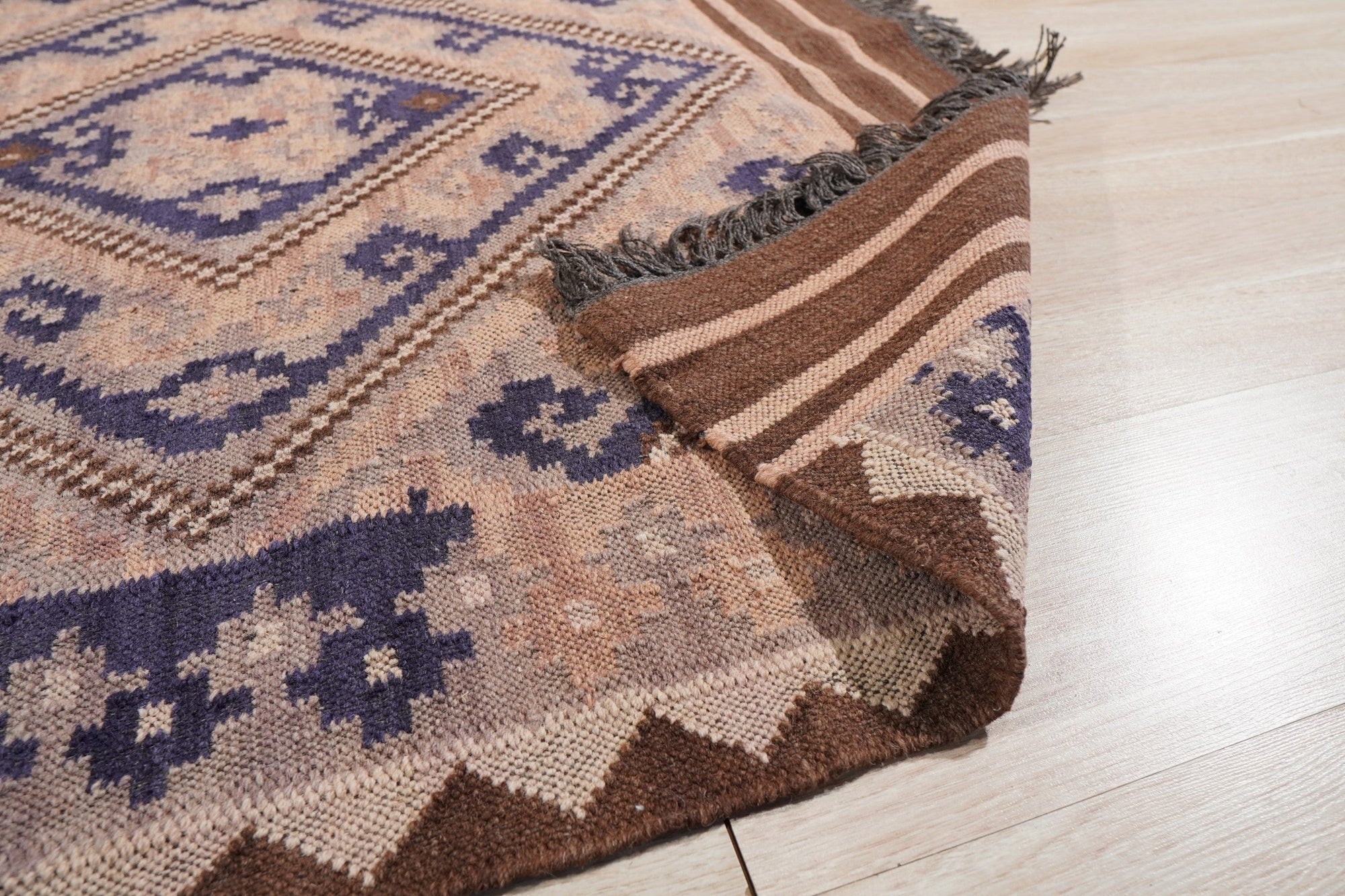 Penelope Jade Brown Flatweave Wool Rug, showing a living room setup with a sofa, coffee table, and the rug anchoring the space. Woven wool creates a warm, inviting texture with a brown and jade color palette.