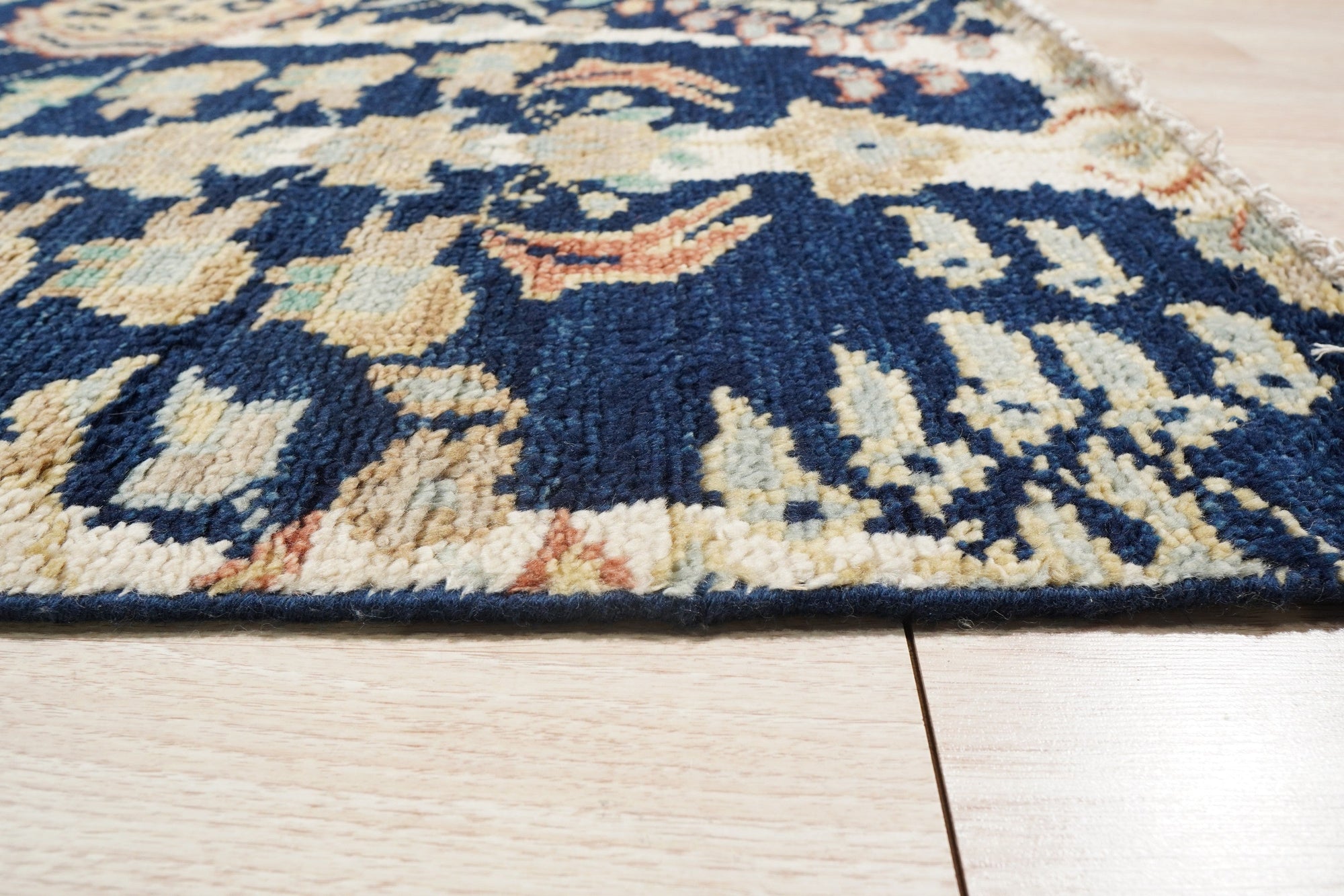Zinnia Louie Blue Hand Knotted Wool Rug, a vibrant floral design rendered in cool blues and creams, showcasing the rug's texture and intricate knotwork.