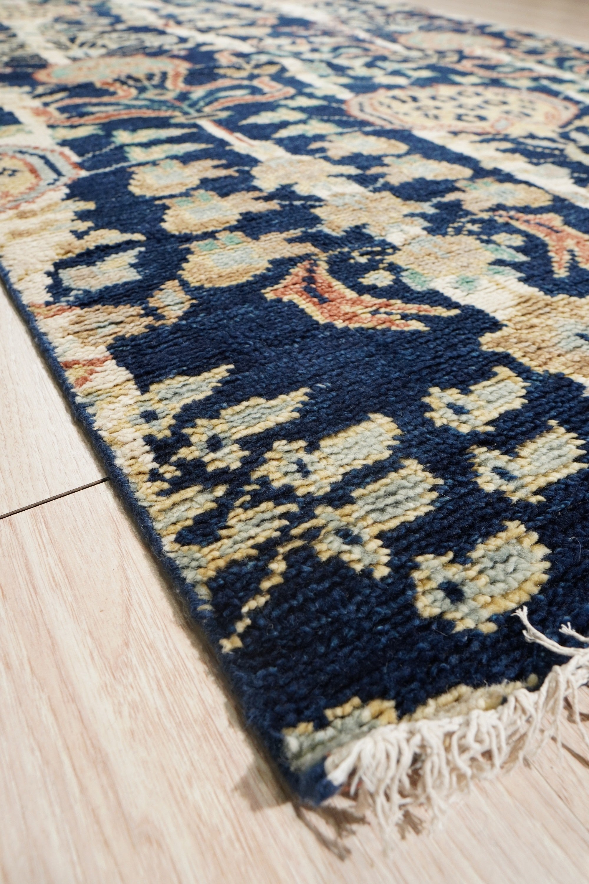 Zinnia Louie Blue Hand Knotted Wool Rug, showcasing its intricate hand-knotted construction and blue color palette, rests on a light floor, adding warmth and texture to a bright, modern living space.