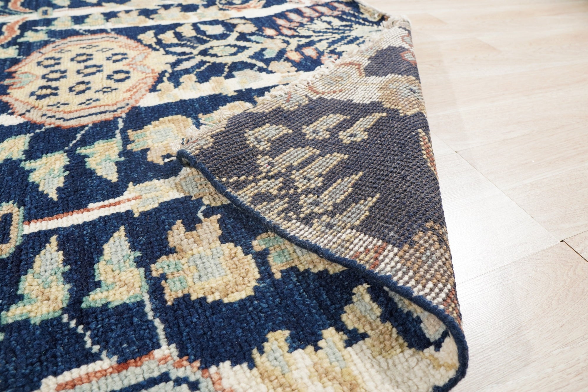 Zinnia Louie Blue Hand Knotted Wool Rug, its intricate floral pattern in shades of blue and cream gracing a light hardwood floor, lending a touch of elegant comfort to the room.
