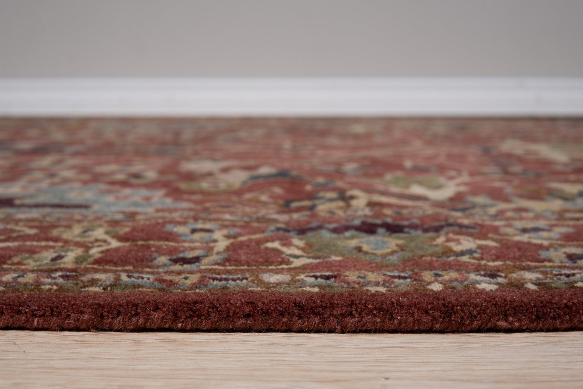 Lydia Vibrant Red Hand Tufted Wool Rug, bold red wool rug with a textured, abstract design, partially visible under a modern coffee table on a light wood floor.