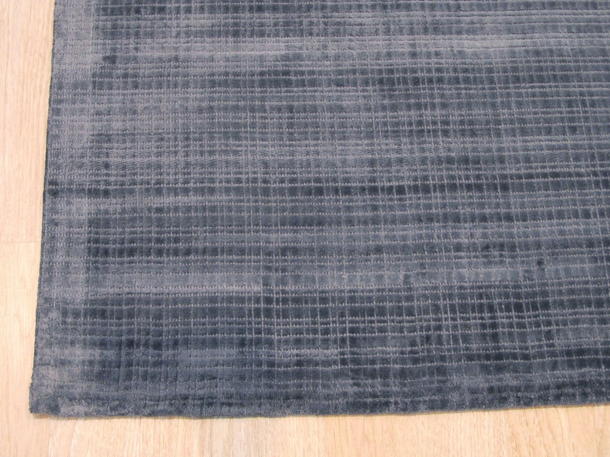 Captivating Lush Blue Handmade Rug displayed in a bright living room setting, showcasing its texture and size. Plush, deep blue tones create a soothing atmosphere, complemented by neutral furniture and natural light.