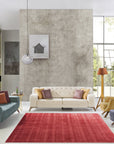 Sophie Iris Red Handmade Rug, vibrant reds and subtle creams swirl across a hand-woven rug, adding warmth and elegance to a brightly lit living space with a mid-century modern aesthetic.