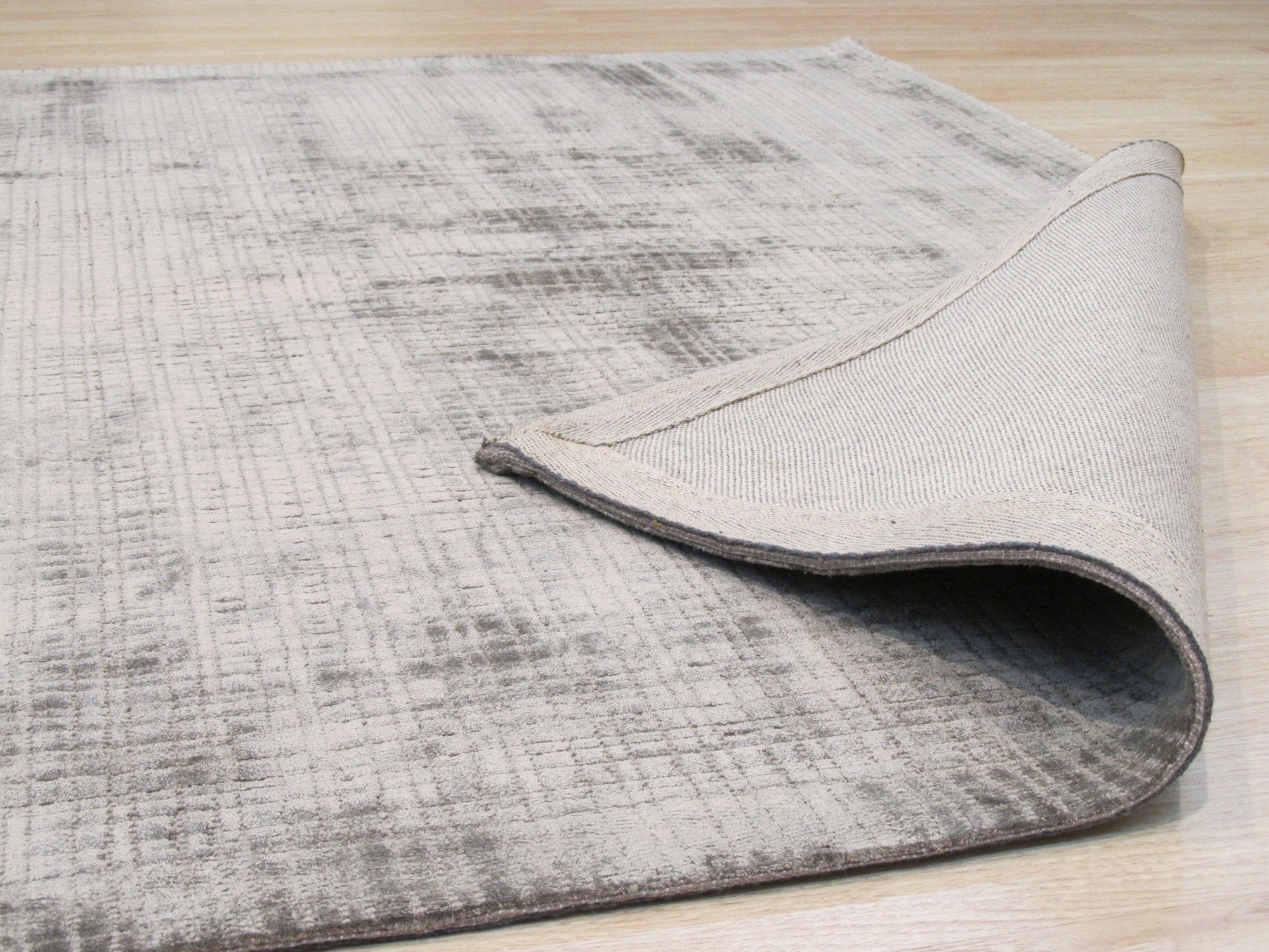 Here's the alt text based on your instructions:
 
 Sloane Maya Silver Handmade Rug, luxurious texture and subtle sheen visible, complementing a bright living space with light wood flooring and minimalist decor.