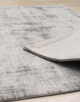 Here's the alt text based on your instructions:
Sloane Maya Silver Handmade Rug, luxurious texture and subtle sheen visible, complementing a bright living space with light wood flooring and minimalist decor.