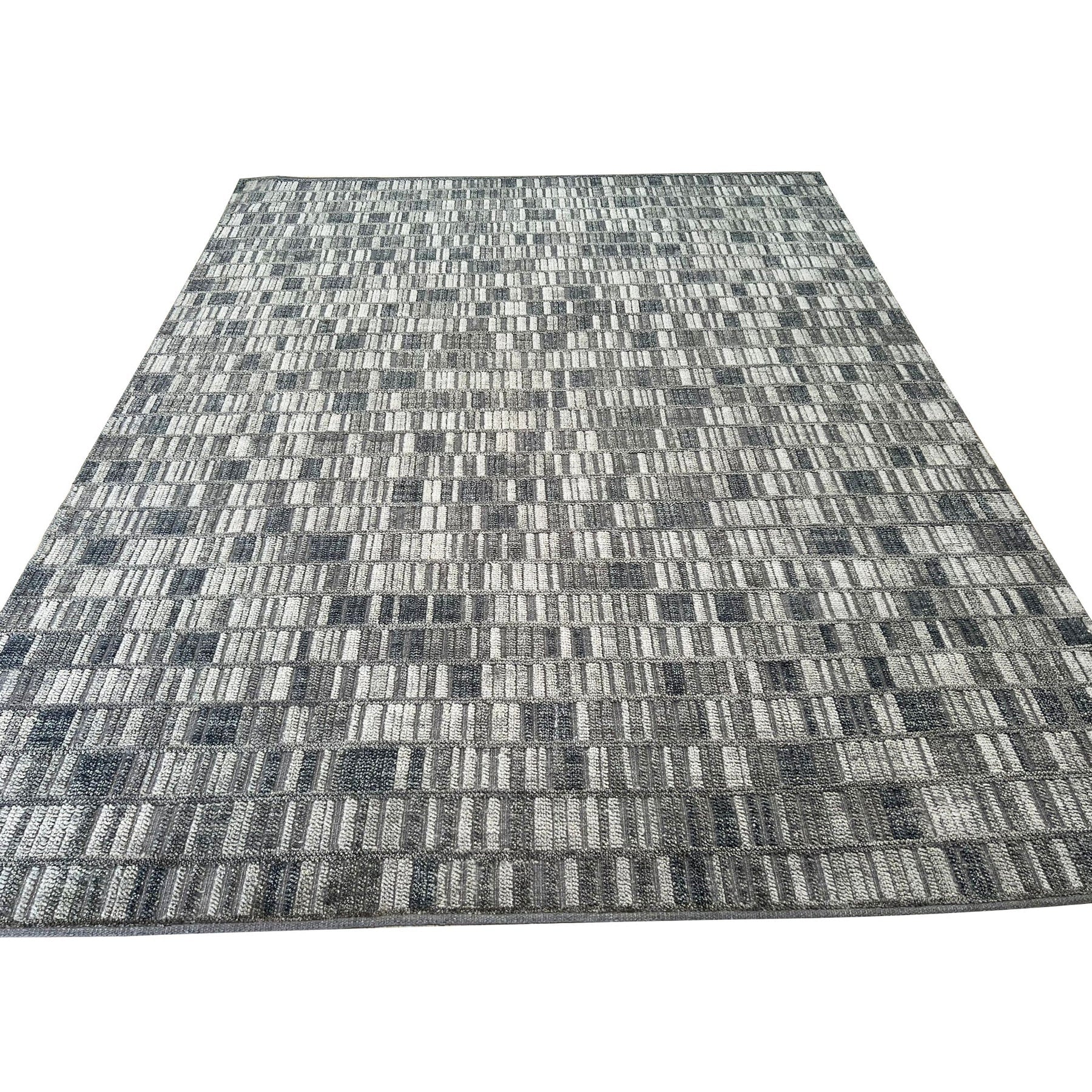 Tessa Sophisticated Gray Hand Knotted Wool Rug, featuring a subtle geometric pattern in shades of gray, complements a modern living room setting with a light wood floor and minimalist decor.