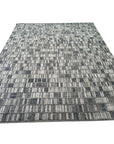 Tessa Sophisticated Gray Hand Knotted Wool Rug, featuring a subtle geometric pattern in shades of gray, complements a modern living room setting with a light wood floor and minimalist decor.