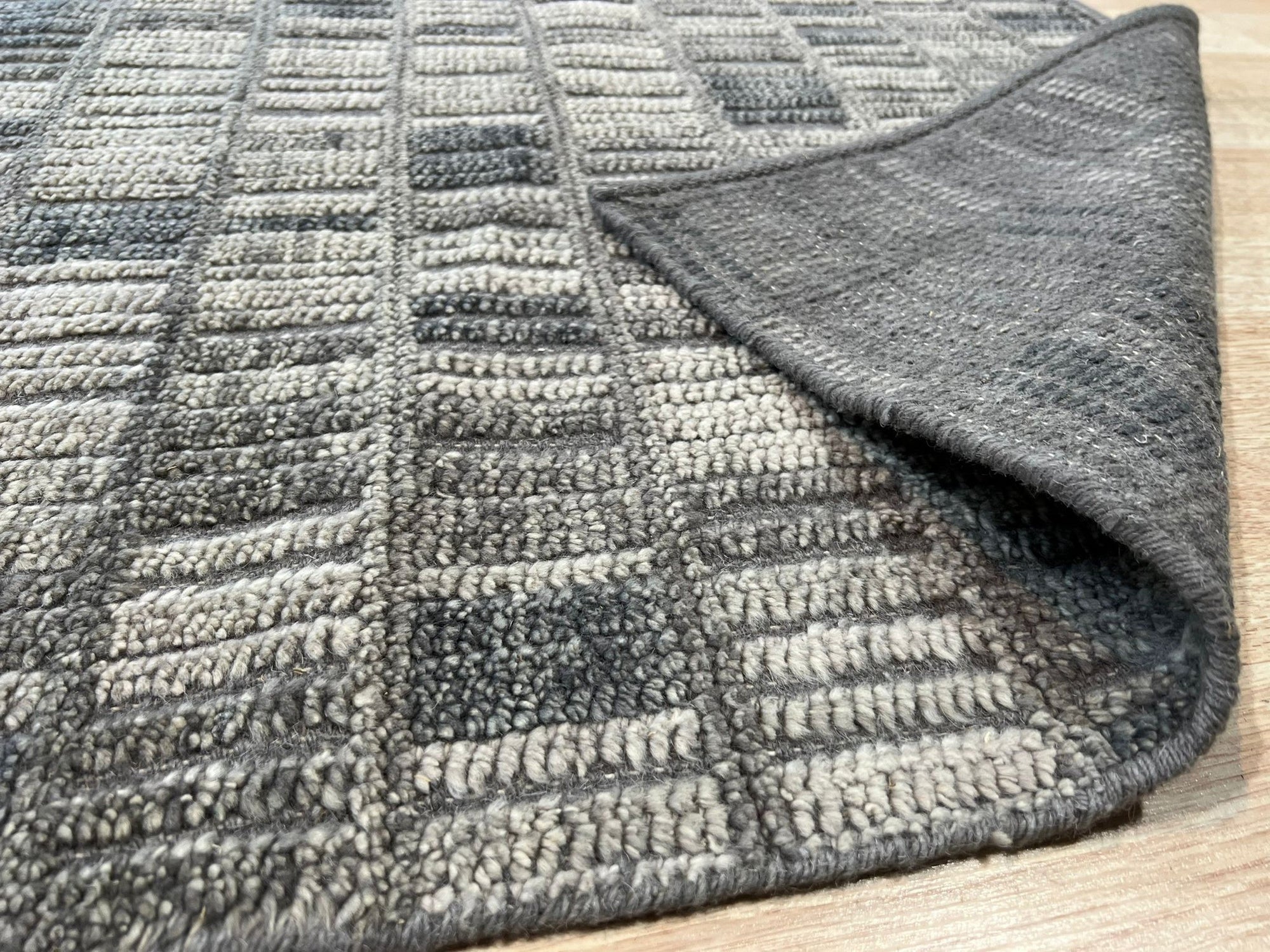 Tessa Sophisticated Gray Hand Knotted Wool Rug, showcasing its subtle grey tones and intricate hand-knotted texture under warm interior lighting.