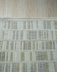 Freya Timeless Ivory Hand Knotted Wool Rug, its intricate pattern unfolds in a bright, warmly lit room; soft textures of wool are discernible underfoot.
