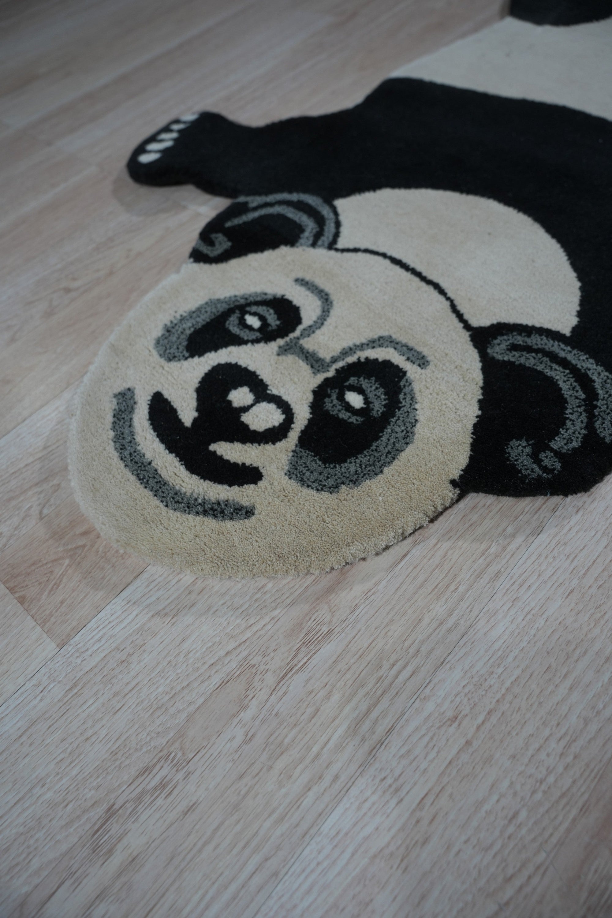 Brenda Clara Black & White Hand Tufted Wool Rug, featuring an abstract geometric pattern in contrasting black and white, lies flat on a light-toned floor, showcasing its texture and design.