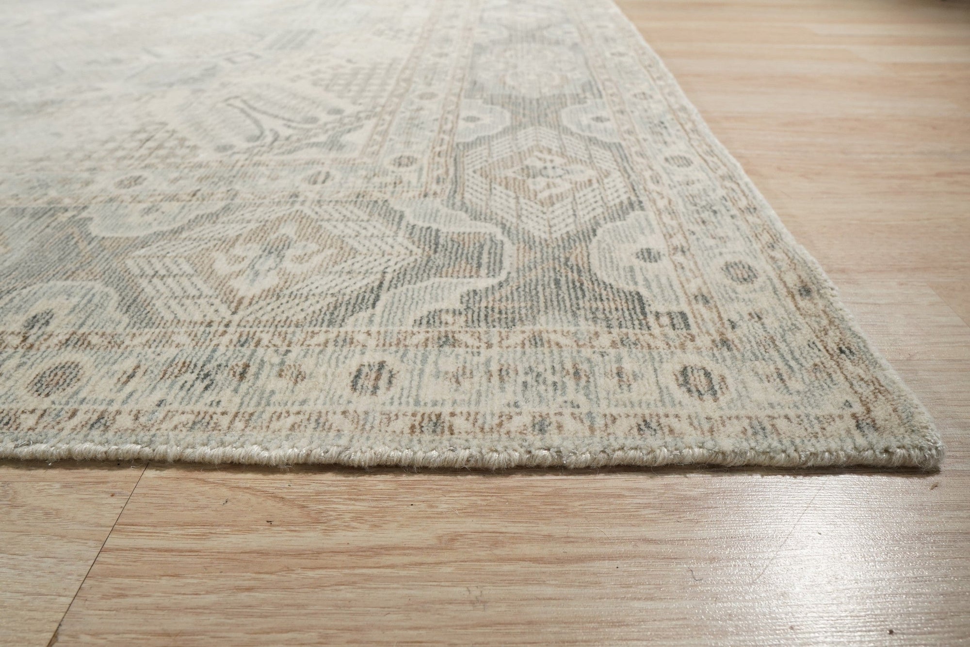 Tessa Bespoke Green Handmade Wool Rug, a deep green and textured wool rug with subtle geometric patterns, laid on light wood flooring and styled with a mid-century modern chair, hinting at a warm, inviting living space.
