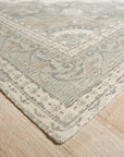 Selene Oriental Green Handmade Wool Rug, showcased in a bright living room setting. Handcrafted wool construction features an intricate oriental pattern in shades of green and cream, grounding the modern decor.