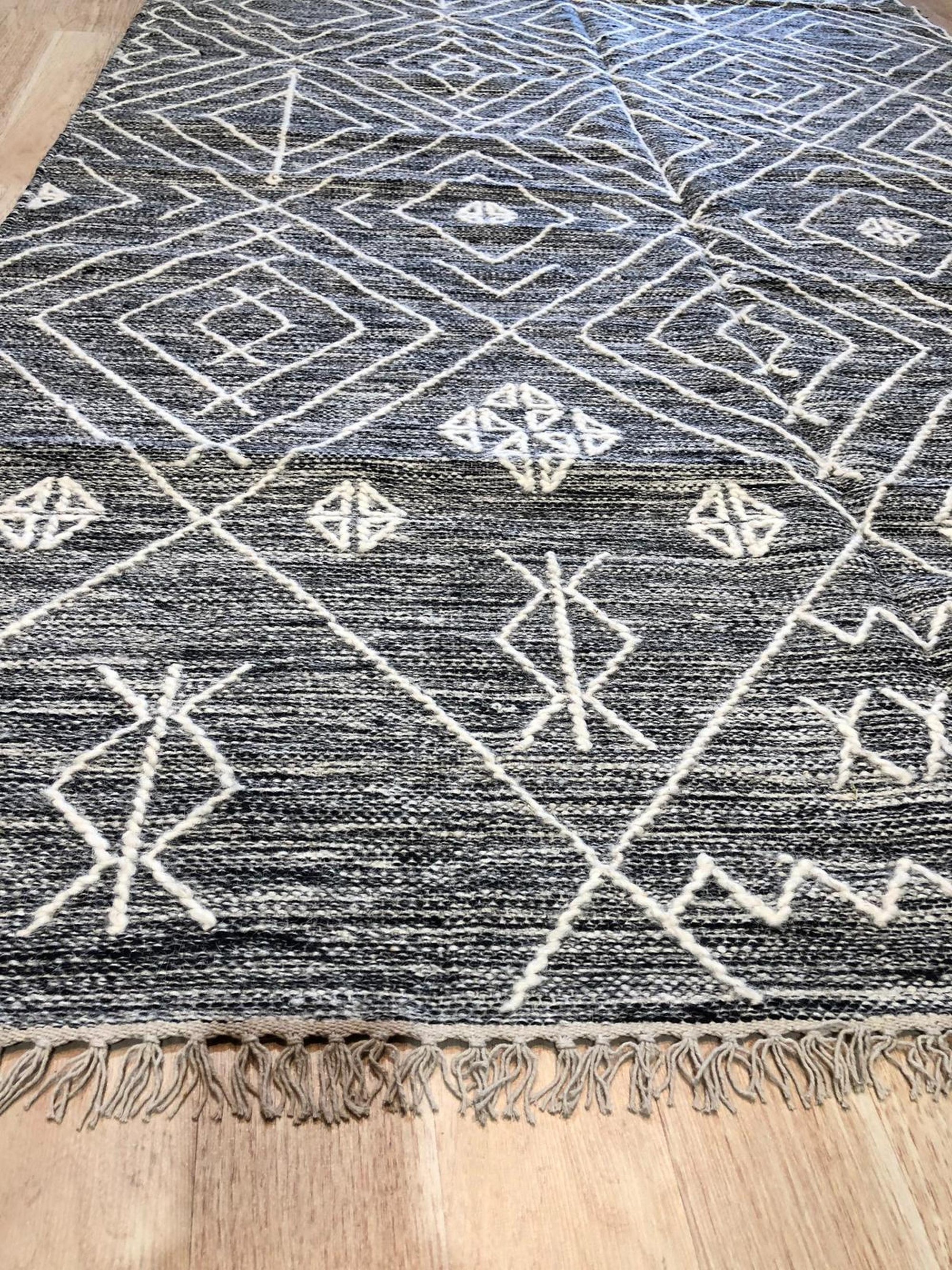 Luxurious Kilim Charcoal Handmade Wool Rug, showcasing a muted charcoal palette and geometric Kilim patterns across its handwoven wool texture, grounding a bright living space.