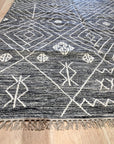 Luxurious Kilim Charcoal Handmade Wool Rug, showcasing a muted charcoal palette and geometric Kilim patterns across its handwoven wool texture, grounding a bright living space.