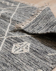 Luxurious Kilim Charcoal Handmade Wool Rug displayed as part of a stylish living room arrangement; charcoal and cream geometric patterns play across its handwoven wool surface, grounding the light-filled space with textured warmth.