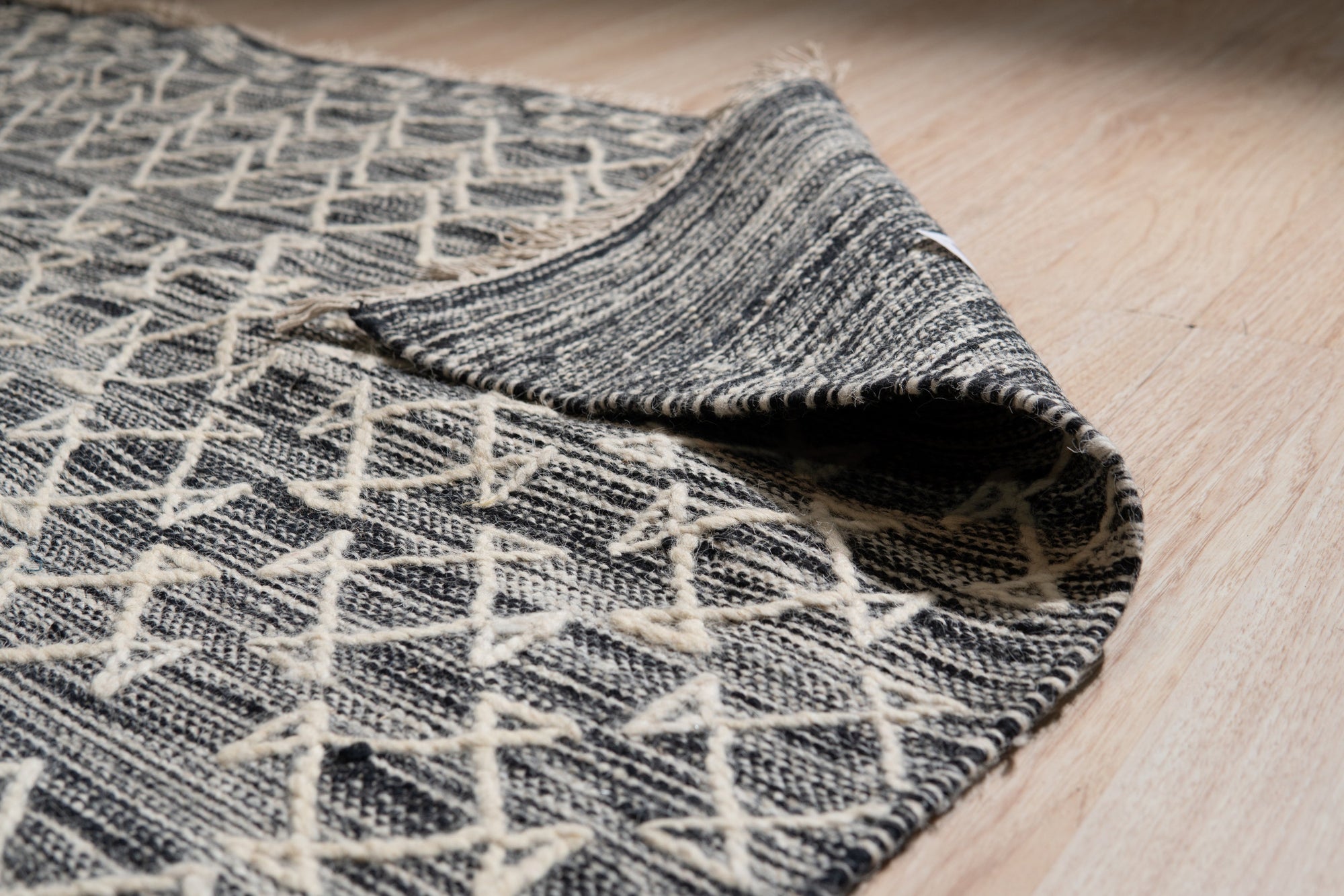 Penelope Kilim Brown Handmade Wool Rug, woven in brown wool with a traditional kilim design, lays flat on a light surface, showcasing its intricate pattern and texture.