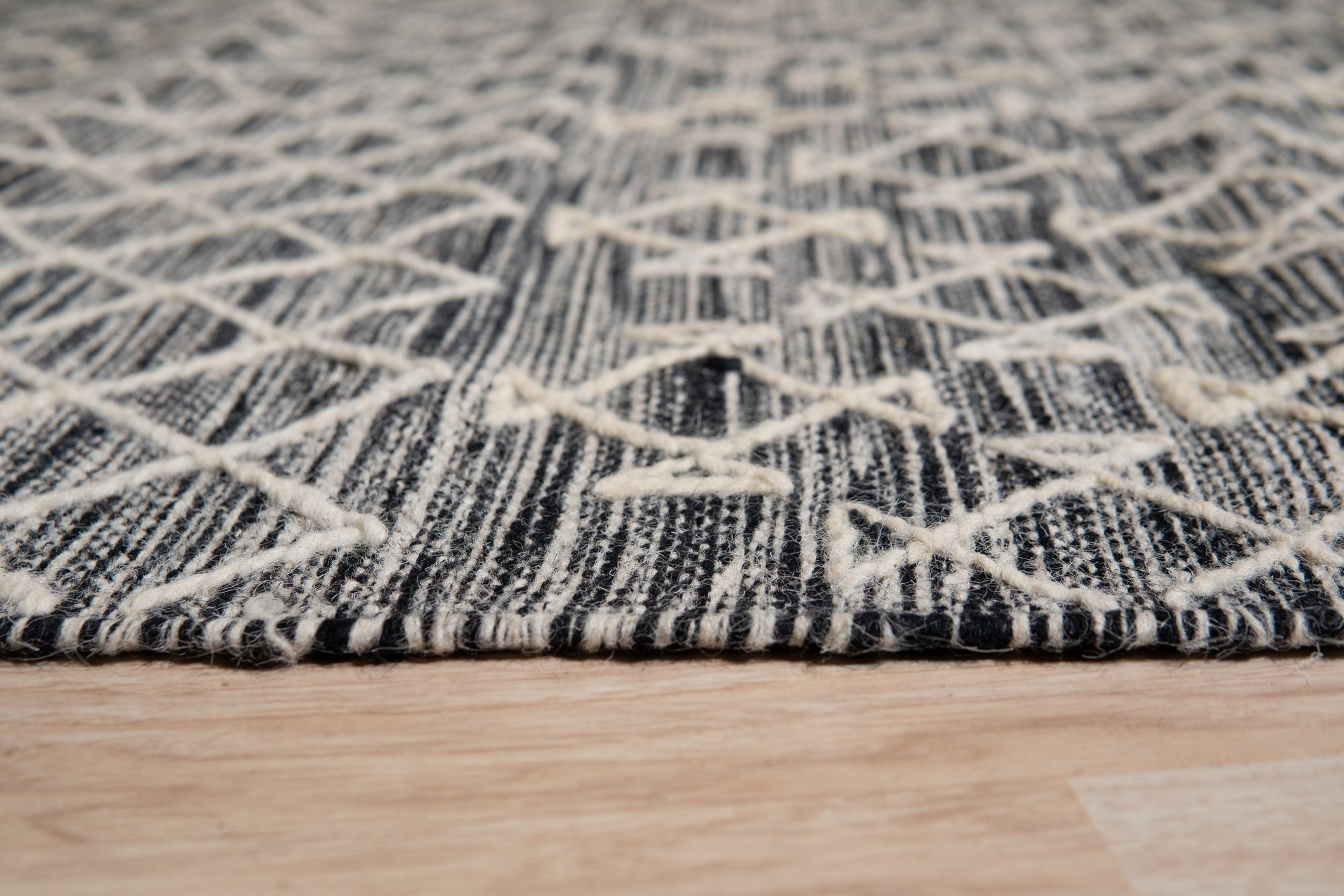 Penelope Kilim Brown Handmade Wool Rug displayed in a bright living room. Warm neutral tones create an inviting space, centered by the handwoven rug. The brown wool rug anchors the seating area, featuring geometric kilim patterns.