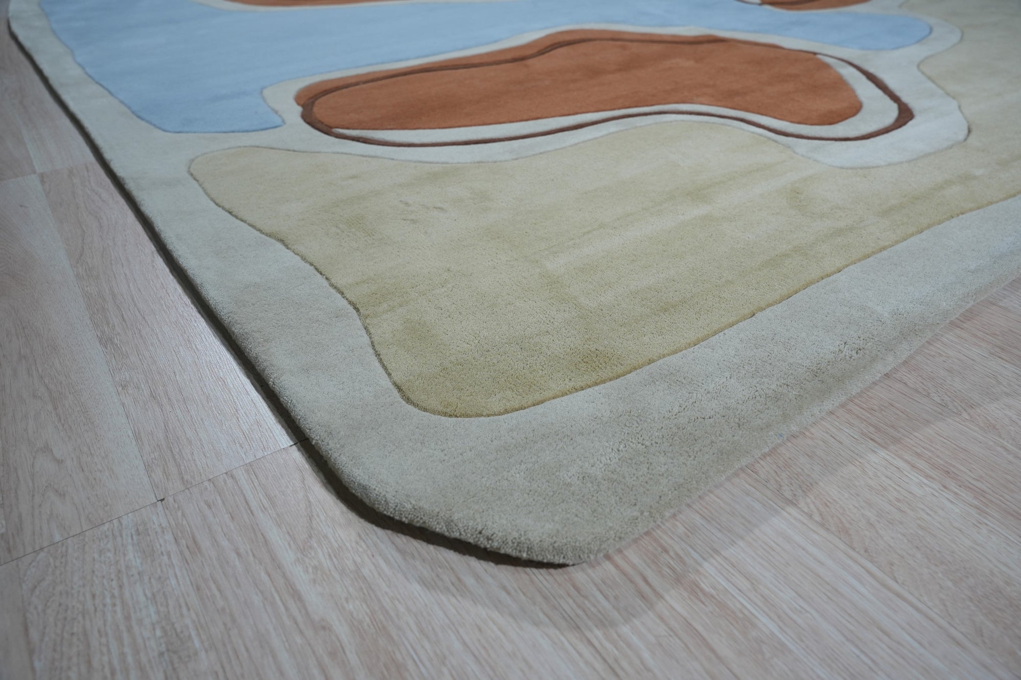 Yara Rustic Blue Hand Tufted Wool Rug, featuring a textured, rustic design in shades of blue, cream, and grey, displayed in a living room setting with a neutral sofa and wooden coffee table.
