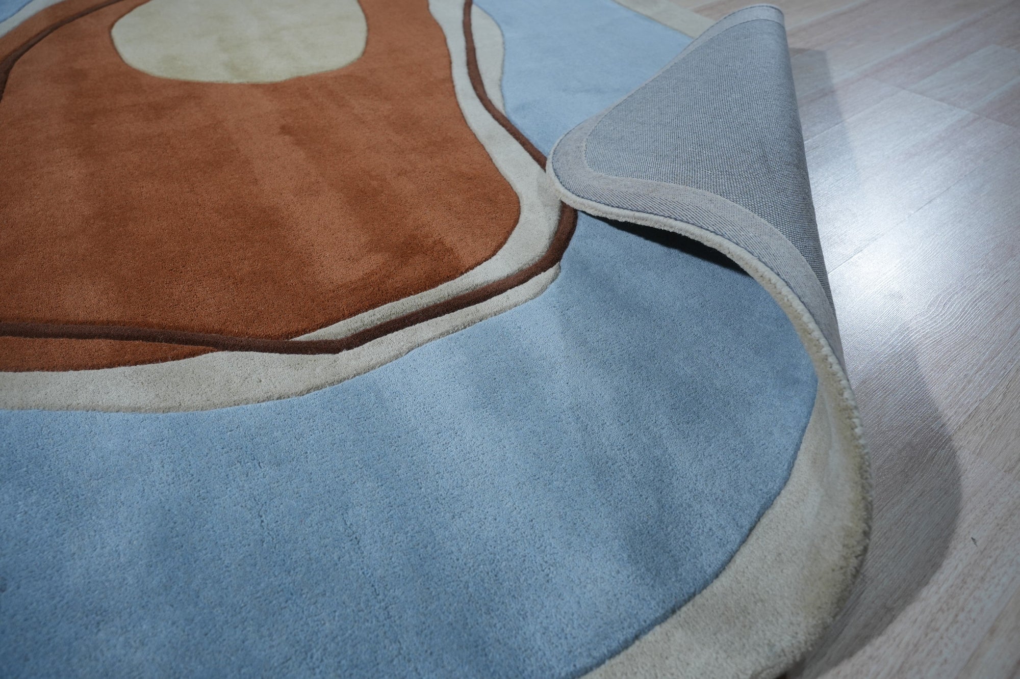 Yara Rustic Blue Hand Tufted Wool Rug, displaying deep blues and creams in a textured, hand-tufted wool construction, complements a naturally lit living space with its warm, inviting presence.