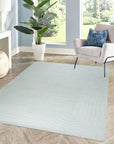 Handcrafted Artisan Ivory Hand Tufted Wool Rug graces a warmly lit living room. Soft, inviting ivory hues and the plush wool texture create a cozy ambiance. The hand-tufted construction is visible in the subtle variations of the pile.