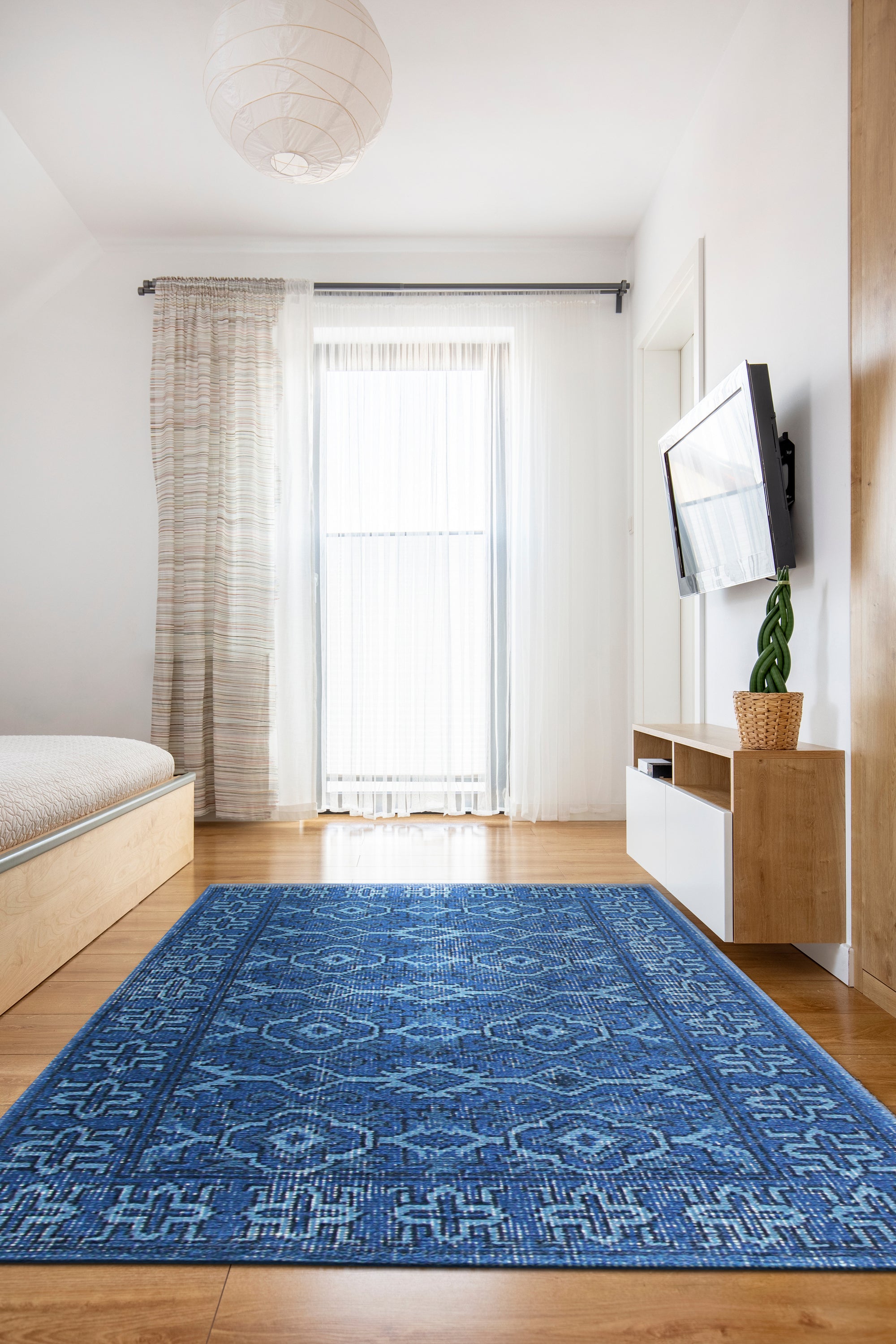 Mira Traditional Blue Hand Knotted Wool Rug, a richly patterned floor covering with deep blues and intricate detailing, adds warmth and elegance to a softly lit room with hardwood floors and neutral walls.