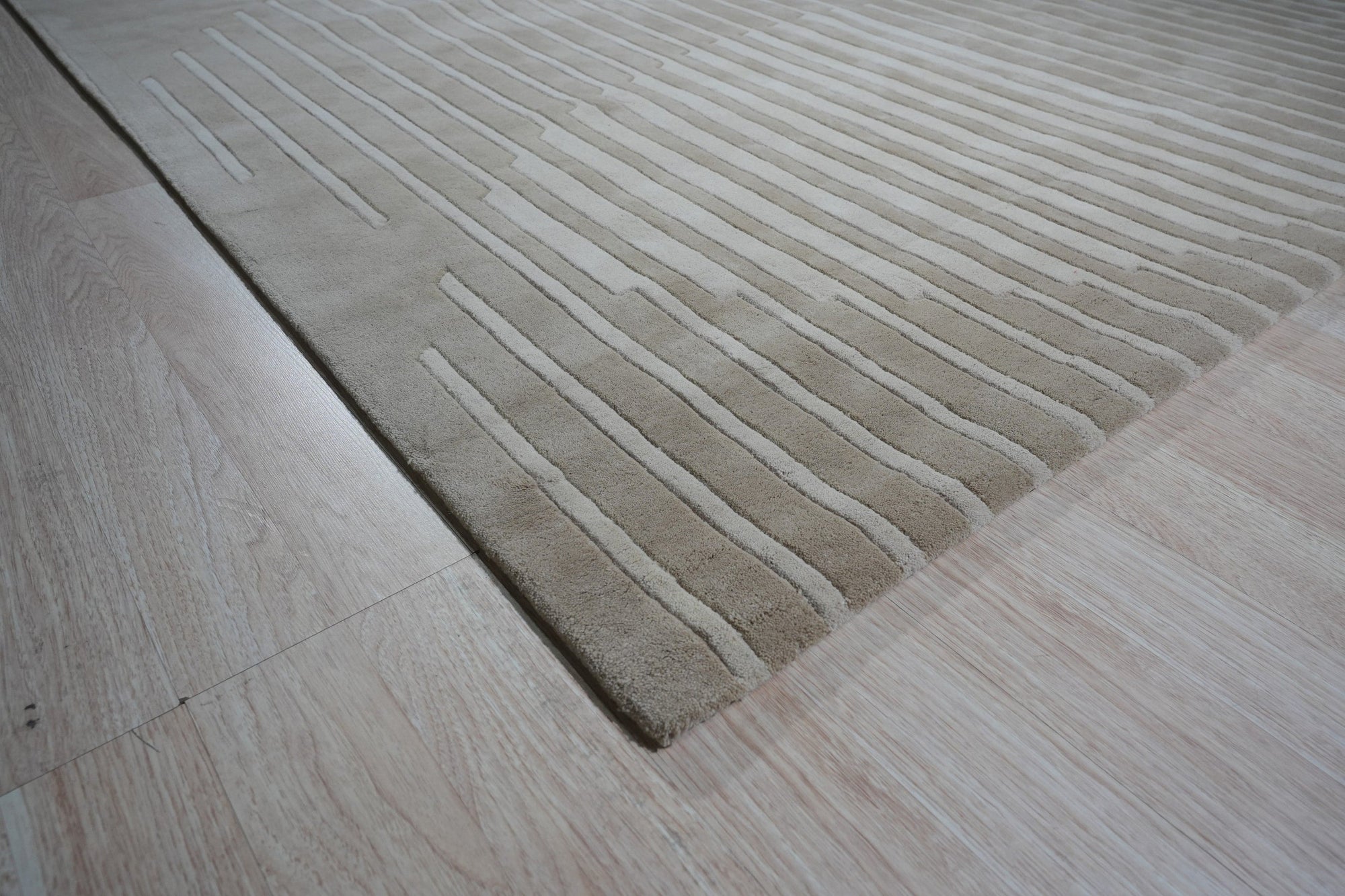 Maya Bianca Beige Hand Tufted Wool Rug, a softly textured beige wool rug with subtle design elements, complements a bright, minimalist living room space.