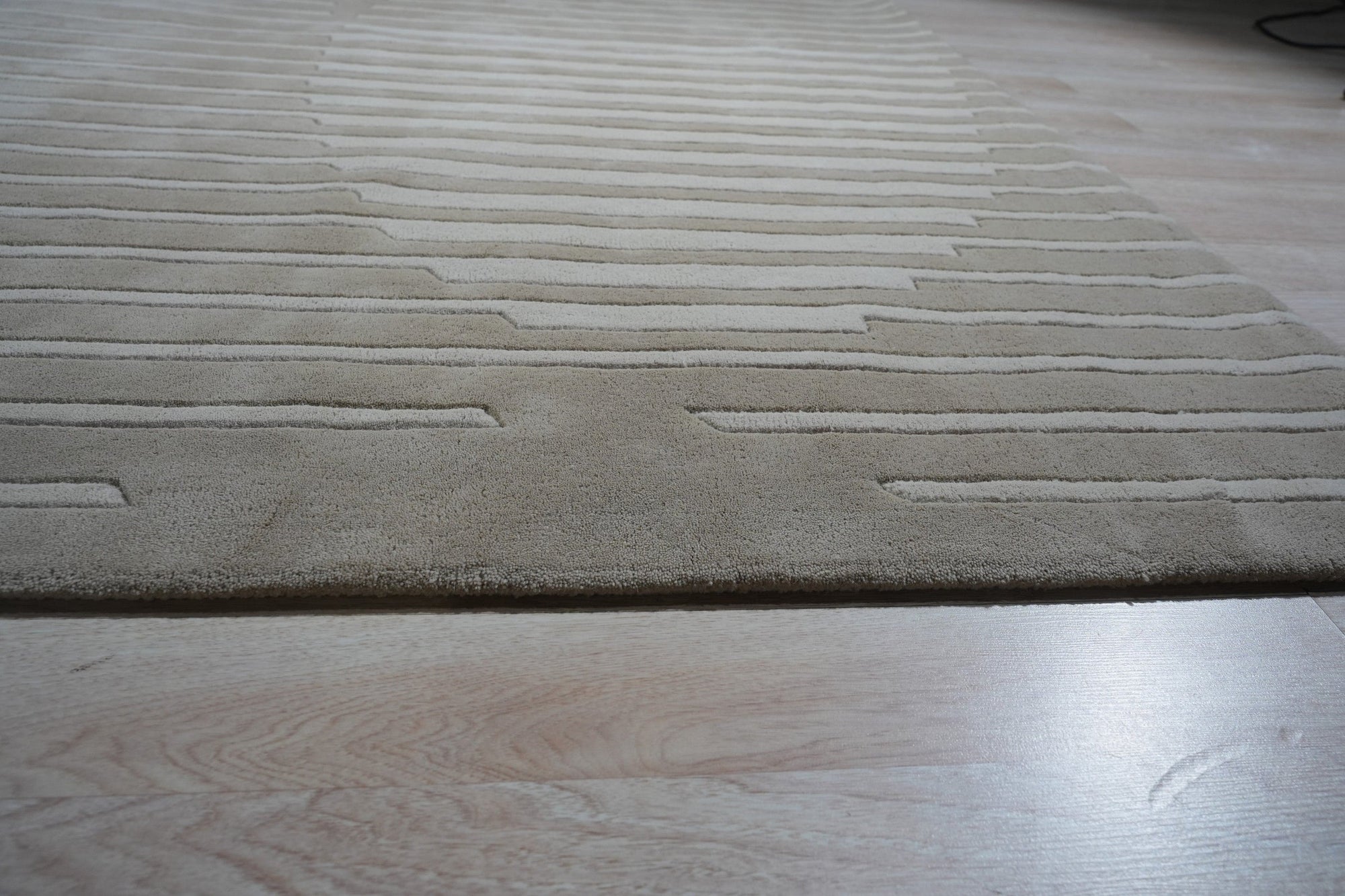 Maya Bianca Beige Hand Tufted Wool Rug, showcasing a subtle geometric pattern in soft beige tones, bringing warmth and texture to a well-lit living space.