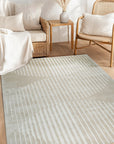 Maya Bianca Beige Hand Tufted Wool Rug, a creamy neutral oasis underfoot, anchors a modern living room with subtle texture and handcrafted warmth. Sunlight highlights the dense wool pile and the rug's calming, minimalist design.