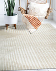 Maya Bianca Beige Hand Tufted Wool Rug, a soft beige wool rug with subtle texture, complements a bright living room with natural light and modern furniture.