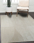 Maya Bianca Beige Hand Tufted Wool Rug, its soft beige hues and hand-tufted texture anchoring a bright, modern living room with natural light streaming through sheer curtains.