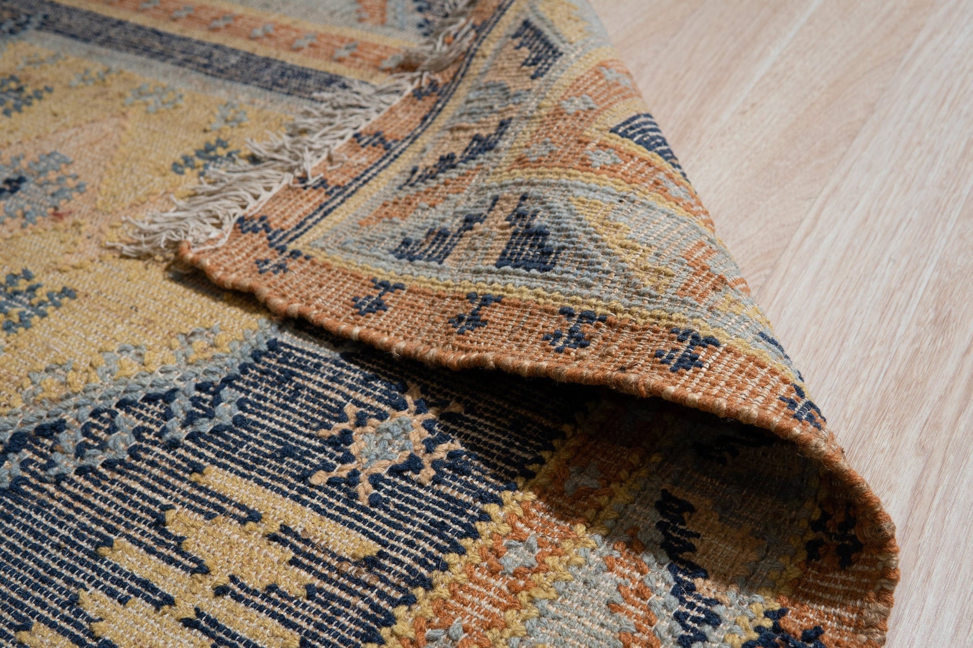 Luna Kilim Blue Hand Knotted Wool Rug, showcasing a geometric design in blues and creams, softly illuminated in a room setting.