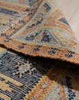 Luna Kilim Blue Hand Knotted Wool Rug, showcasing a geometric design in blues and creams, softly illuminated in a room setting.