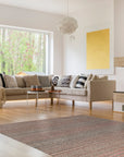 Fiona Striped Navy Handmade Rug displayed in a bright, modern living room. Blue and white stripes run horizontally across the woven rug, grounding the light furniture and adding a touch of coastal charm.