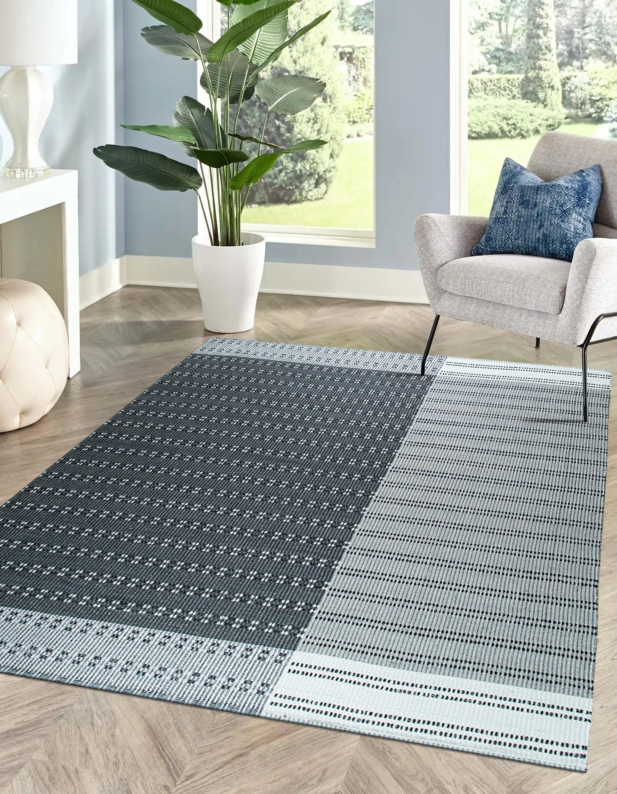 Clara Xena Charcoal Flatweave Wool & Cotton Rug, a textured charcoal rug with a subtle geometric pattern, laid on a light wood floor in a bright, modern living space.