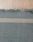 Opulent Majestic Blue Flatweave Wool Rug, its deep blues and subtle variations enriching a bright living space. The flatweave construction allows for a low profile, grounding a coffee table adorned with books and decor.
