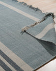Opulent Majestic Blue Flatweave Wool Rug, a rich blue wool rug with a subtle geometric pattern, partially visible in a warmly lit room with hardwood flooring, hinting at its elegant presence.