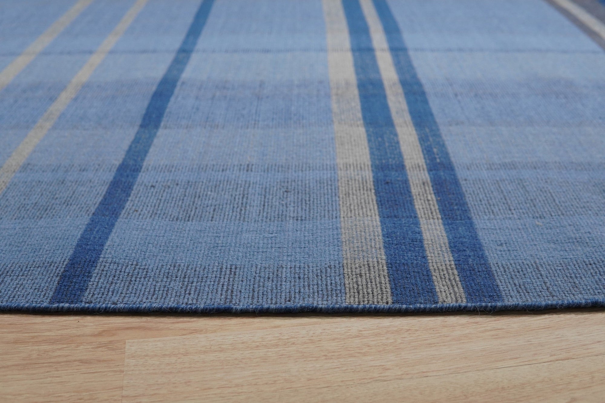 Maya Opulent Blue Flatweave Wool Rug, a serene expanse of indigo and sapphire hues woven in a durable flatweave construction, offers textural richness and modern elegance underfoot.