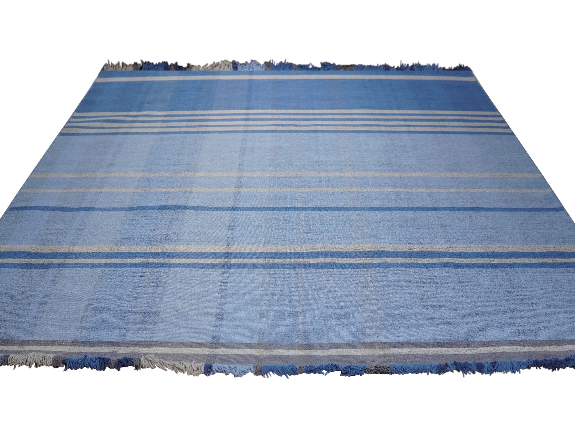 Maya Opulent Blue Flatweave Wool Rug, blending cool blue hues in a flatweave construction, graces a contemporary living space with minimalist furniture and warm lighting.