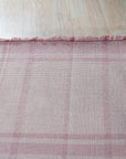 Maya Giselle Pink Flatweave Wool Rug in a bright living room setting. The flatweave construction showcases the rug's subtle texture and delicate pink hues, anchoring the space with understated elegance.
