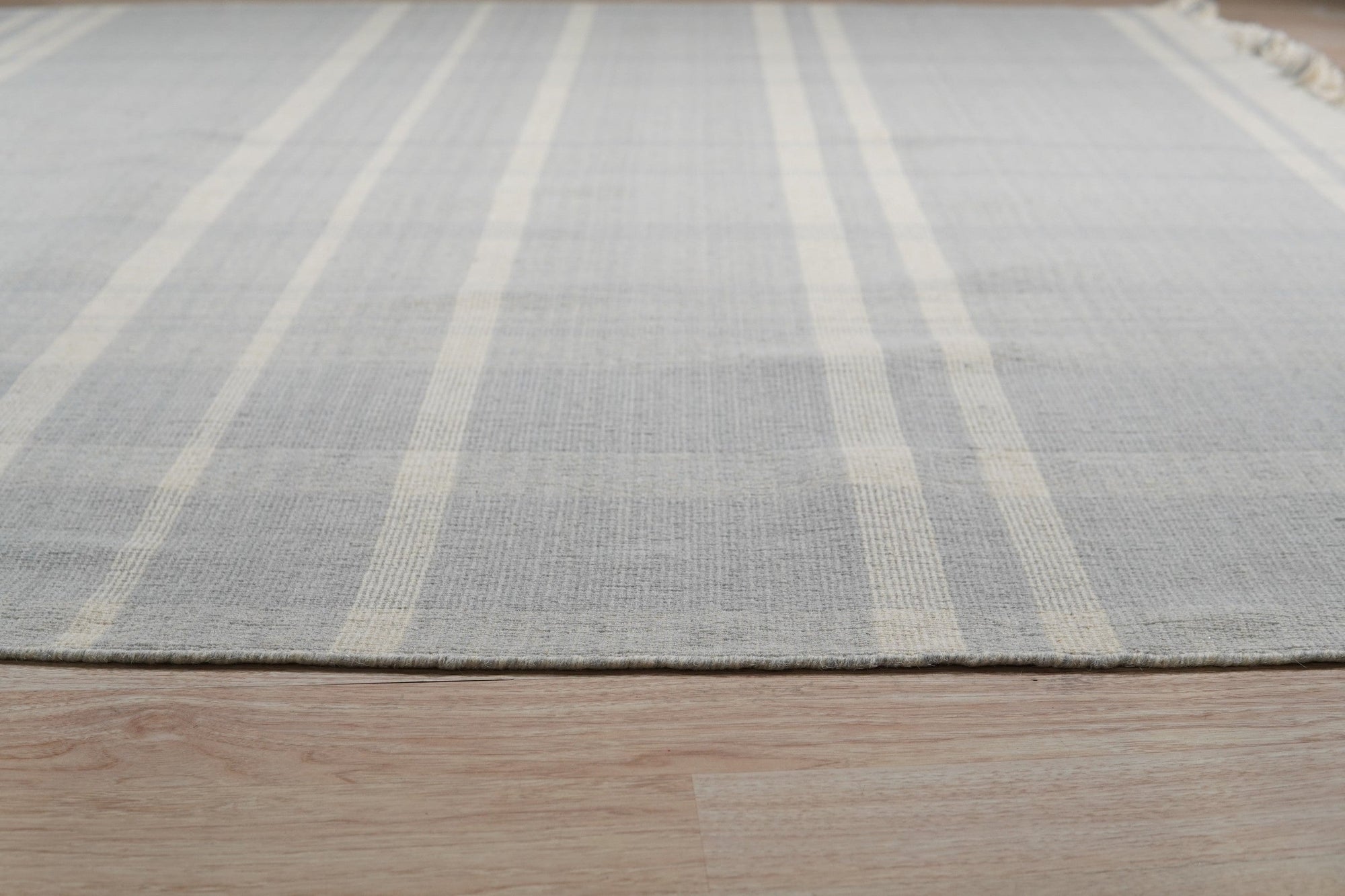 Dazzling Fiona White Flatweave Wool Rug gracing a bright, contemporary living space. Light wood furniture complements the rug's crisp white wool, emphasizing its flatweave construction and minimalist design.