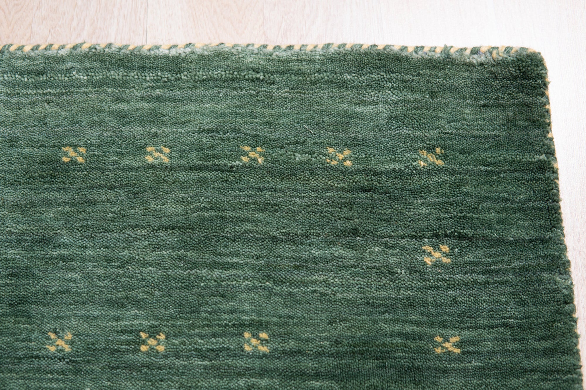 Sloane Ava Green Handmade Wool Rug, seen in a bright living room setting. Woven textures and subtle tonal variations in green add depth to the room's modern aesthetic.