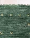 Sloane Ava Green Handmade Wool Rug, seen in a bright living room setting. Woven textures and subtle tonal variations in green add depth to the room's modern aesthetic.