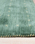 Sloane Ava Green Handmade Wool Rug, showcasing a modern living room setting with a light wood coffee table atop the green and cream patterned rug.
